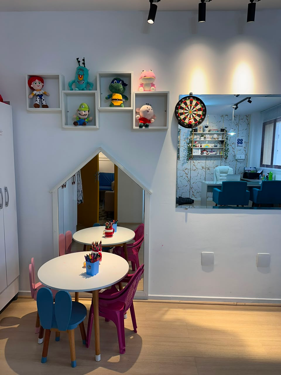 Espaço infantil lúdico com mesinha, cadeiras e nichos de brinquedos