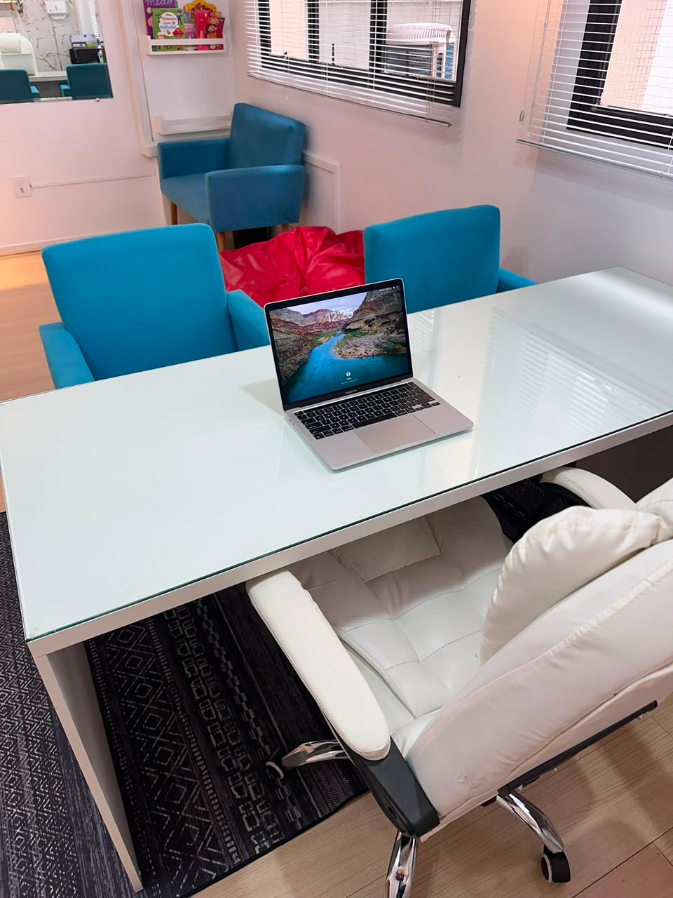 Sala de atendimento com mesa de vidro e poltronas azuis