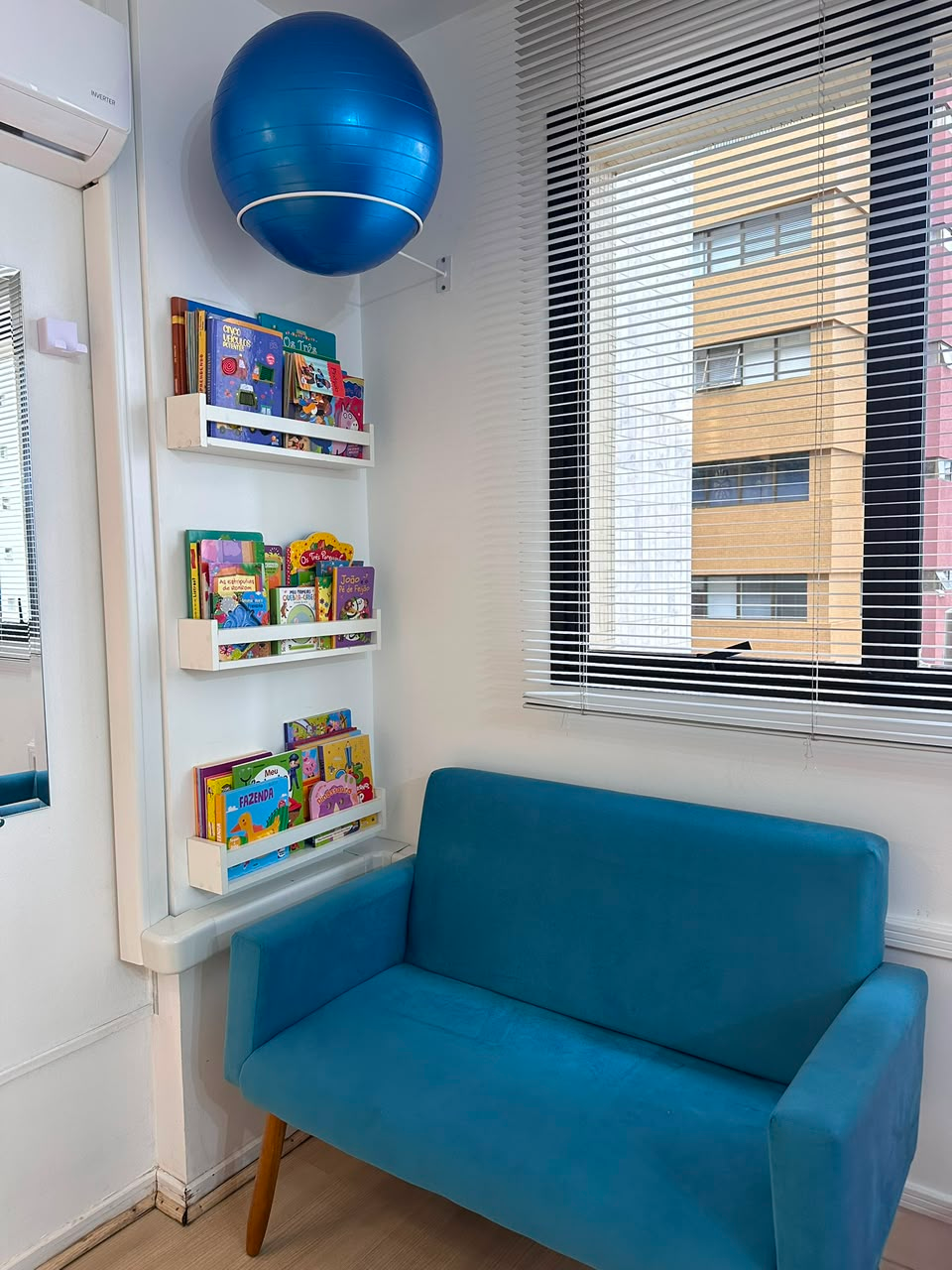 Cantinho de leitura infantil com estante de livros e poltrona azul